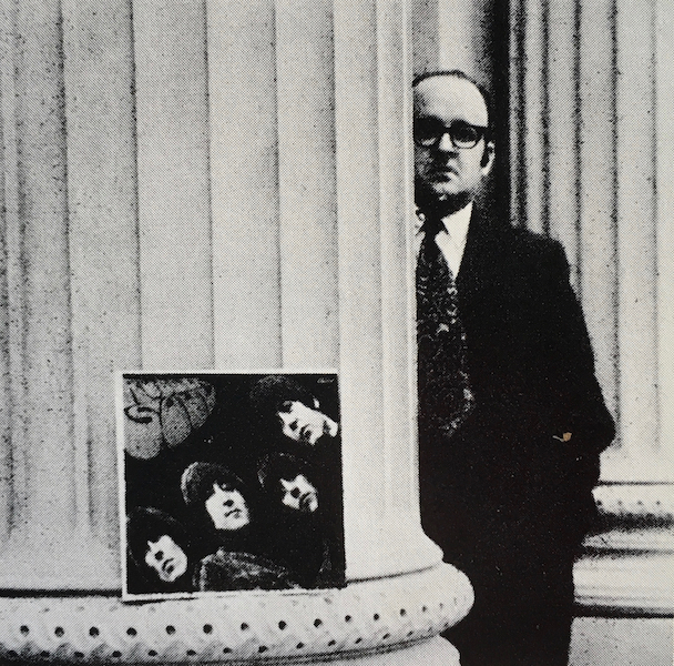 Robert Fulford next to a pillar and album cover for Rubber Soul