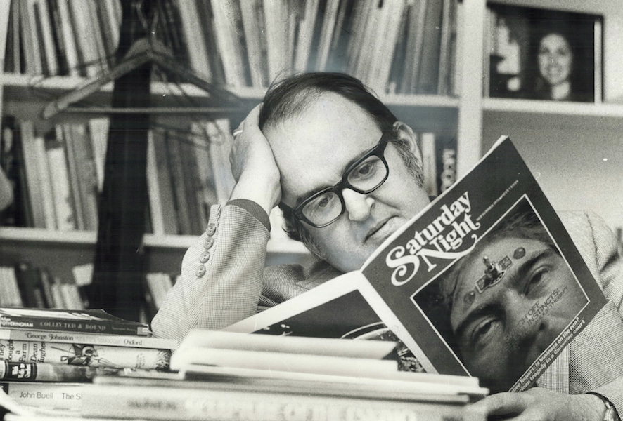 Robert Fulford in his office reading an issue of Saturday Night magazine